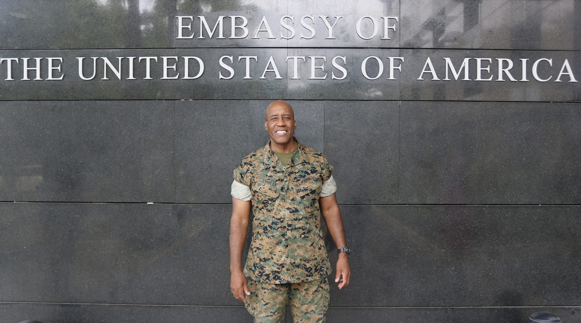 U.S. Marine Corps Gen. Michael Langley, commander, U.S. Africa Command stands in front of a Embassy of the United States sign